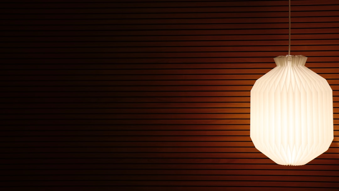 Papieren hanglamp met warme gloed tegen een houten wand