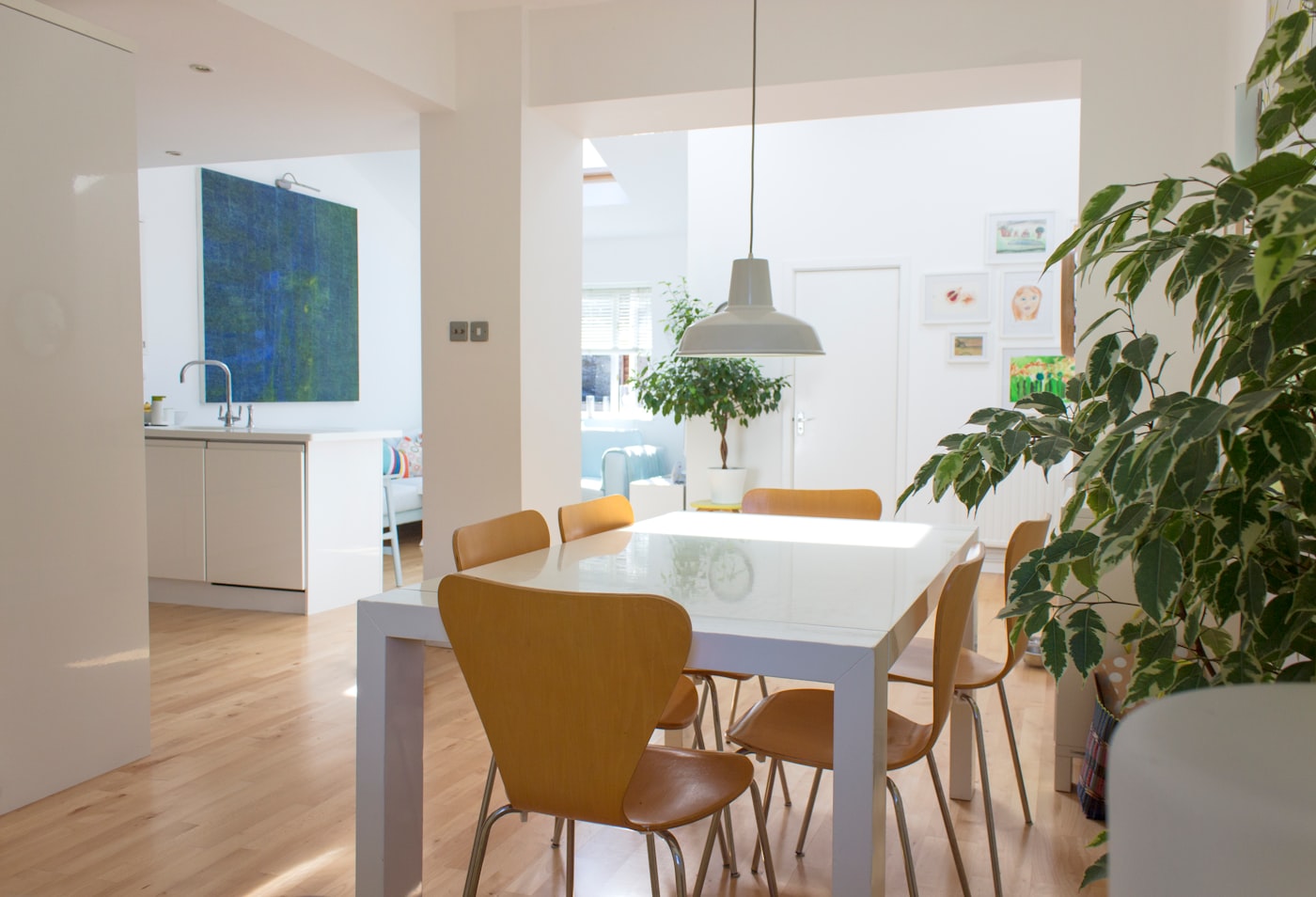 Lichte houten eetkamerstoelen met gebogen zitschaal rond een eettafel in een licht interieur
