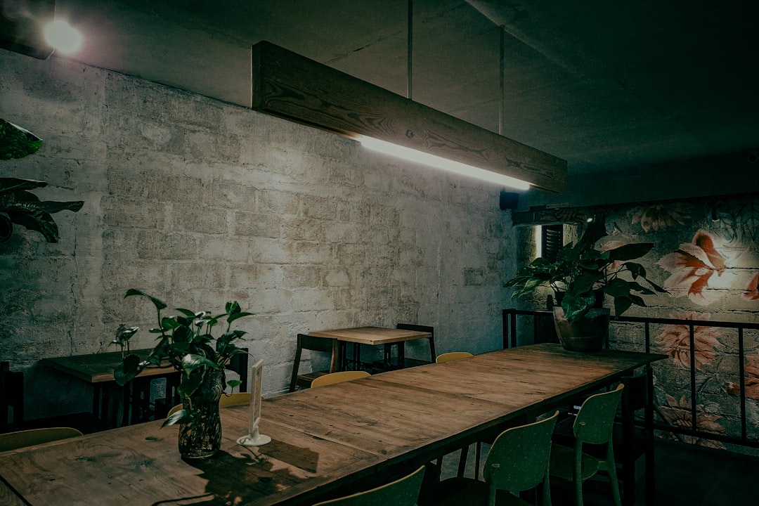 Lange houten eettafel met stalen onderstel tegen een ruwe bakstenen muur