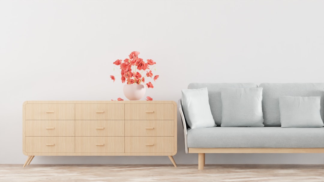 Licht eiken dressoir met poten tegen een witte muur naast een bank