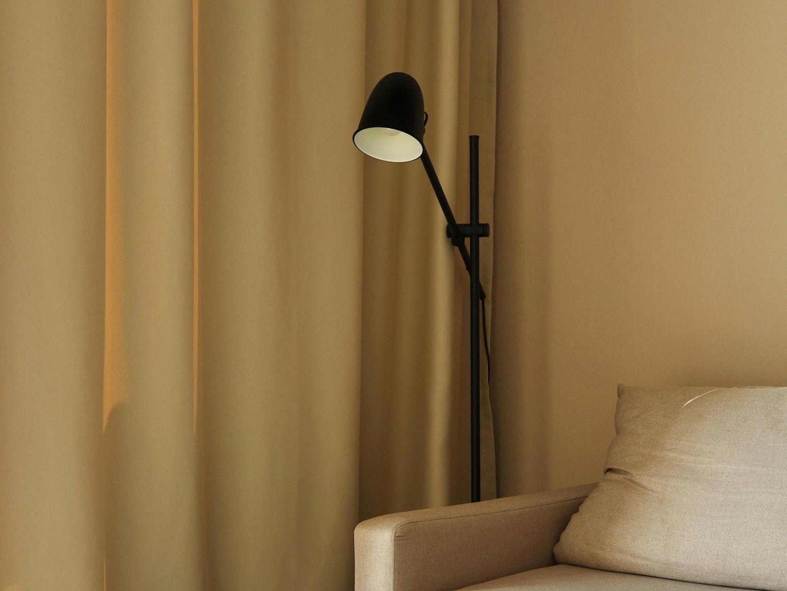 Zwarte Scandinavische vloerlamp met verstelbare arm naast een lichte bank