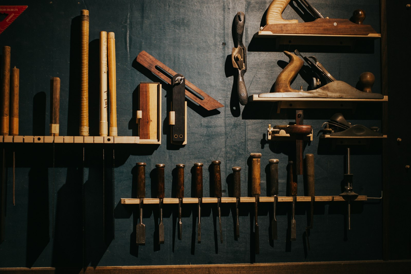 Handen van een meubelmaker die met een beitel aan een houten onderdeel werkt
