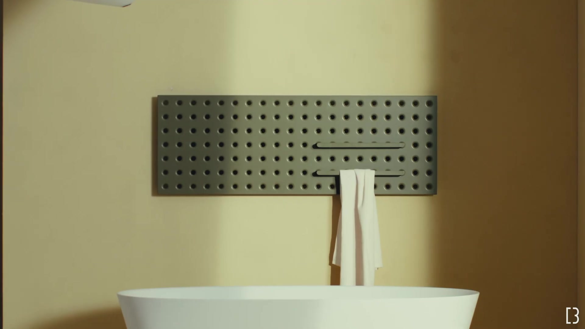 Grijze geperforeerde Grid-radiator liggend boven een wasbak met een handdoek in de stang