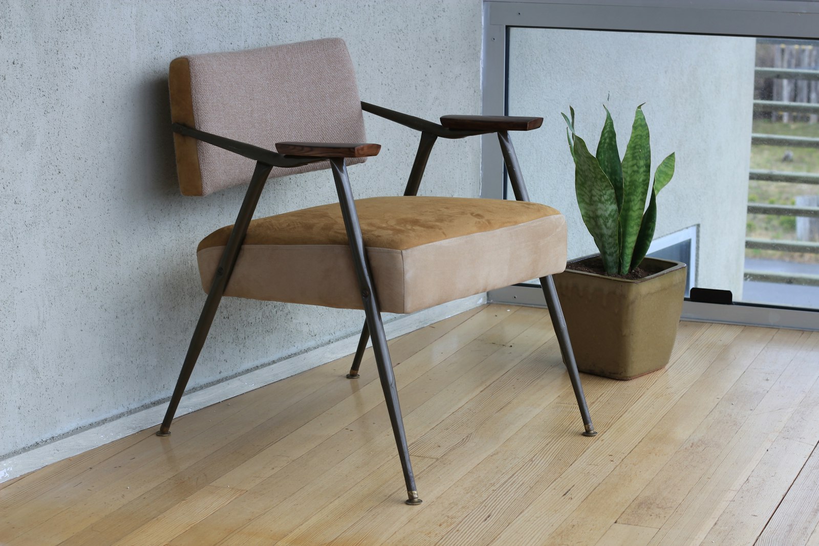 Walnoten dressoir met messing grepen naast een cognackleurige leren fauteuil
